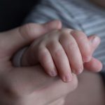 persons hand on top of blue textile